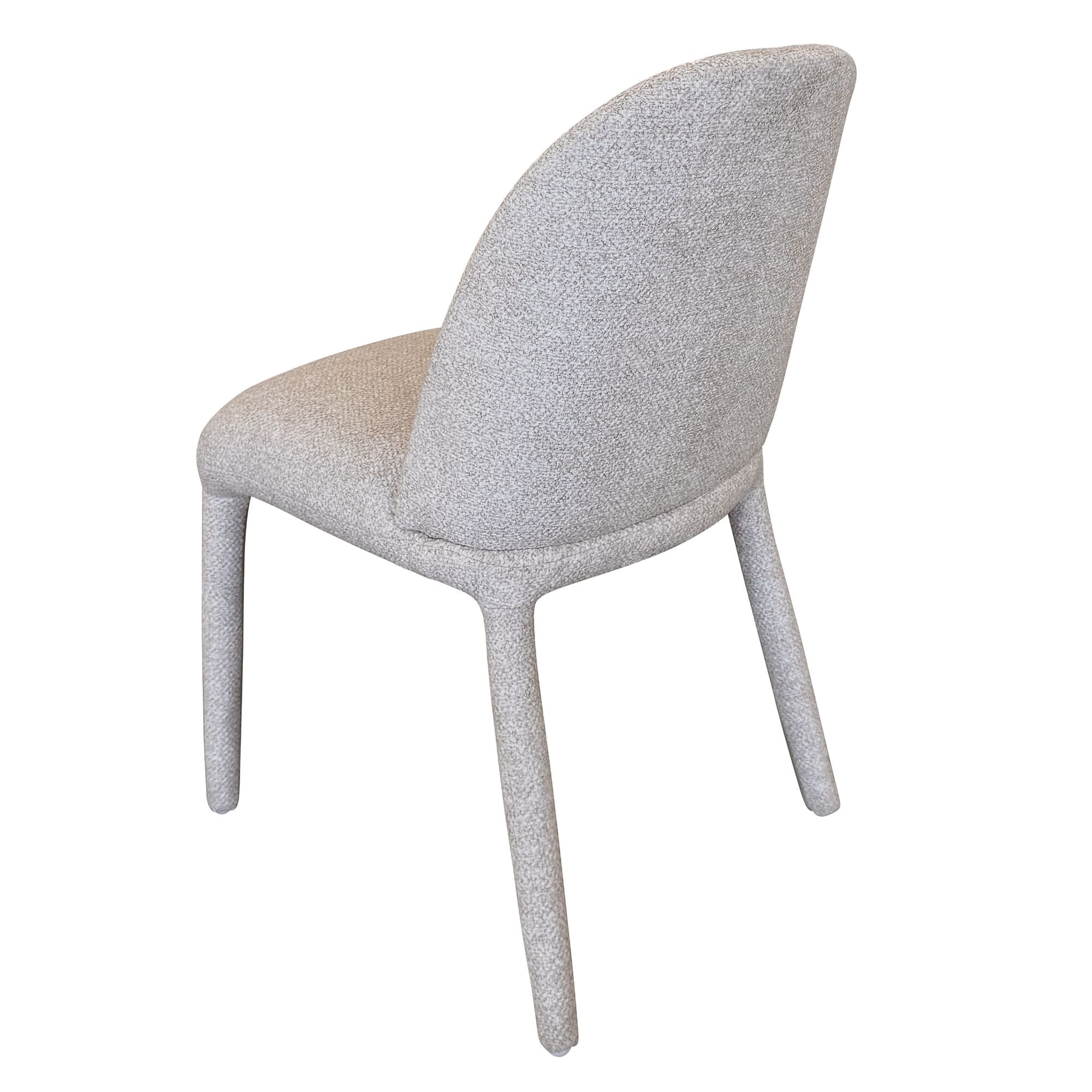 Angled back view of the Myla fully upholstered dining chair in a light beige speckled fabric.