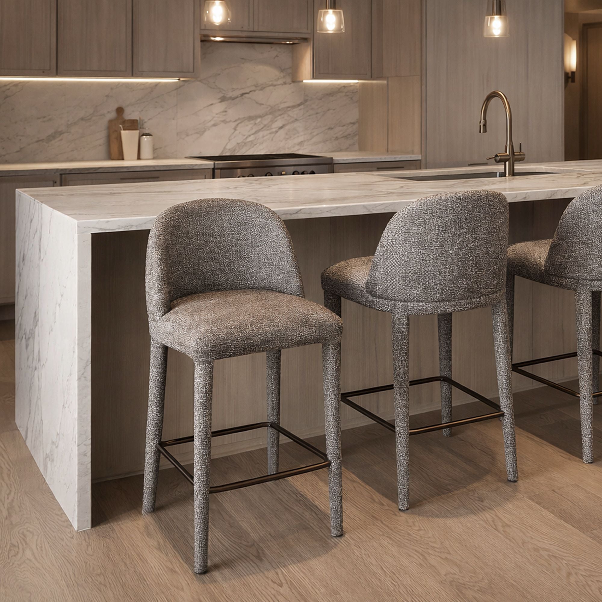 Two light grey textured Myla counter stools styled at a white marble kitchen island next to a home bar setup.