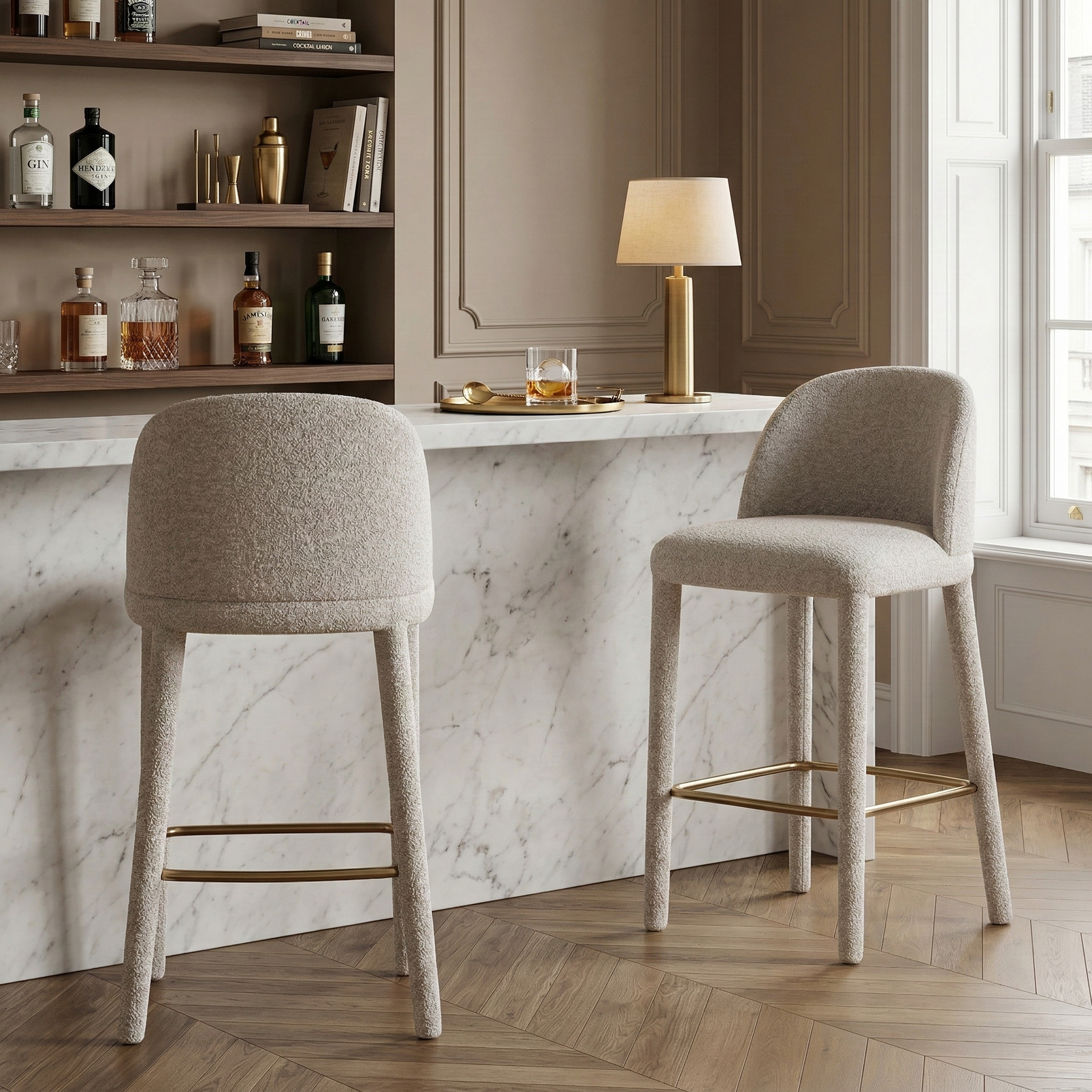 Two textured beige Myla counter stools styled at a white marble kitchen island in an elegant home bar setting.