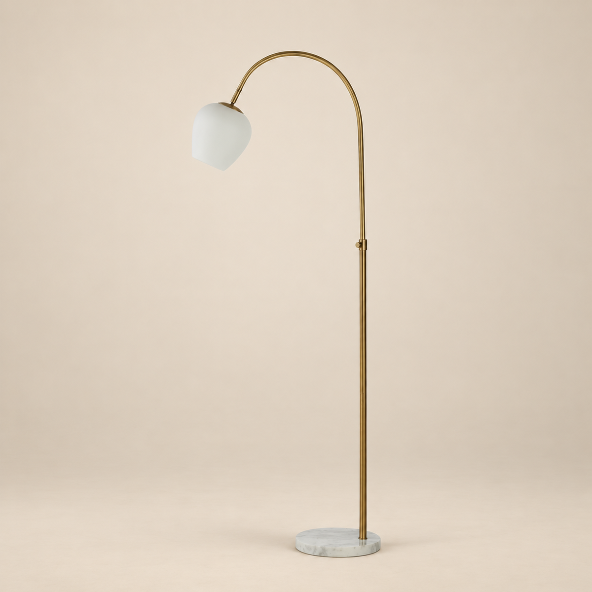 Noemi marble arc floor lamp featuring a plated antique brass frame and opal glass shade on a beige studio background.