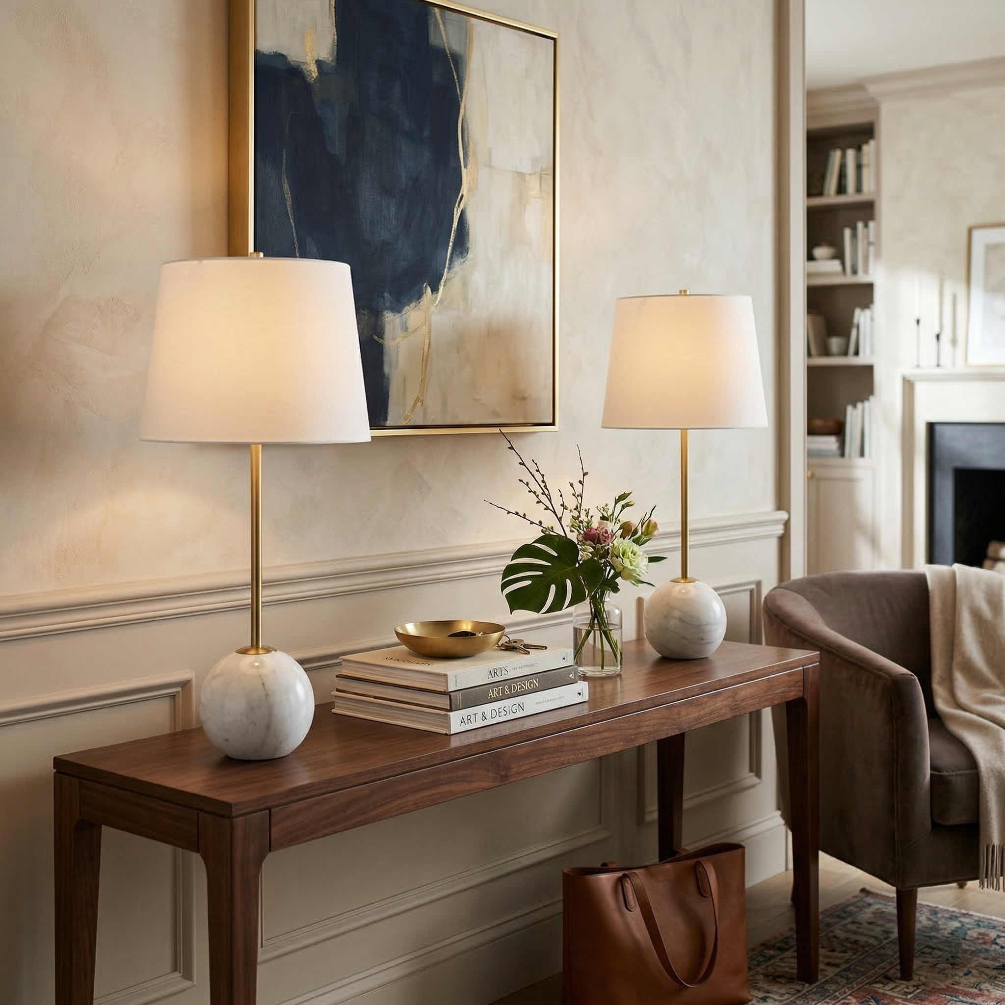 The white Nox marble orb lamps styled on a walnut console table with abstract art in a contemporary room.
