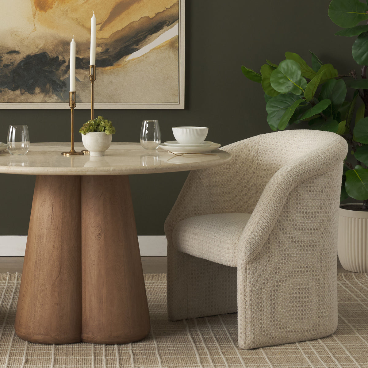 Octavia cream dining armchair styled beside a round stone and wood dining table