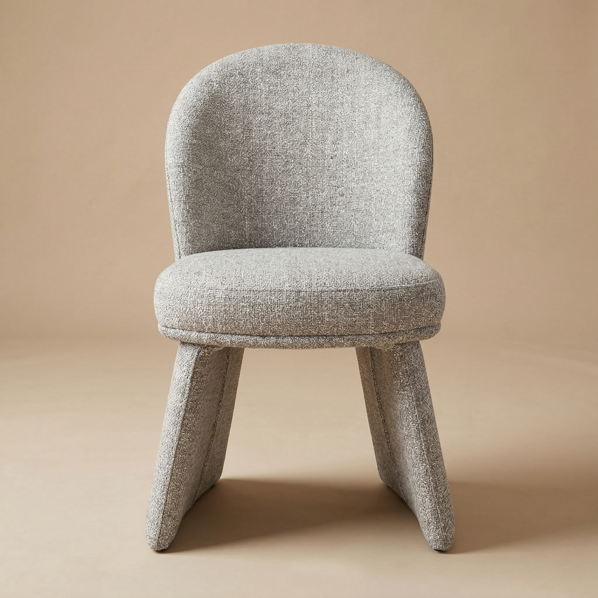 Full front view of the Odette bouclé chair showcasing its curved backrest and unique monolithic upholstered base.