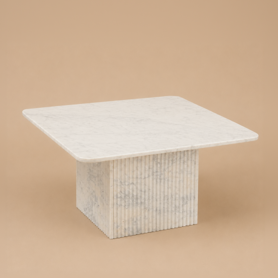 Square marble table with a marble top and fluted base on a beige studio