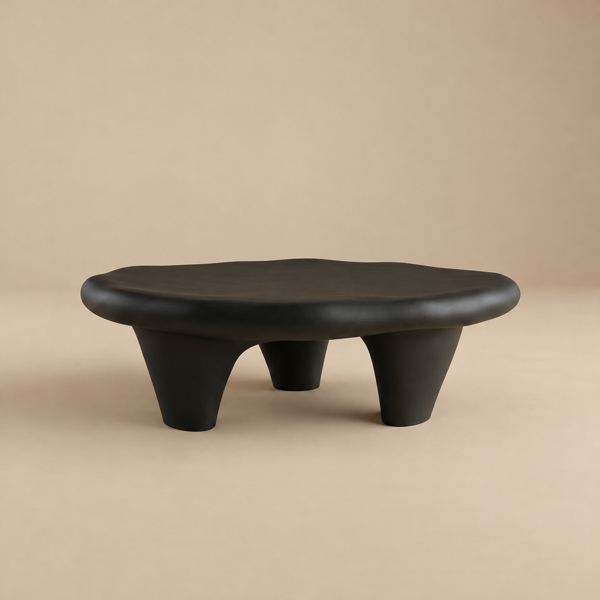 Front view of the matte black pebble coffee table highlighting its sculptural low-profile design.