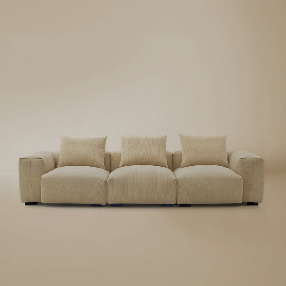 Beige plush corduroy modular sofa in sectional configuration in a studio background