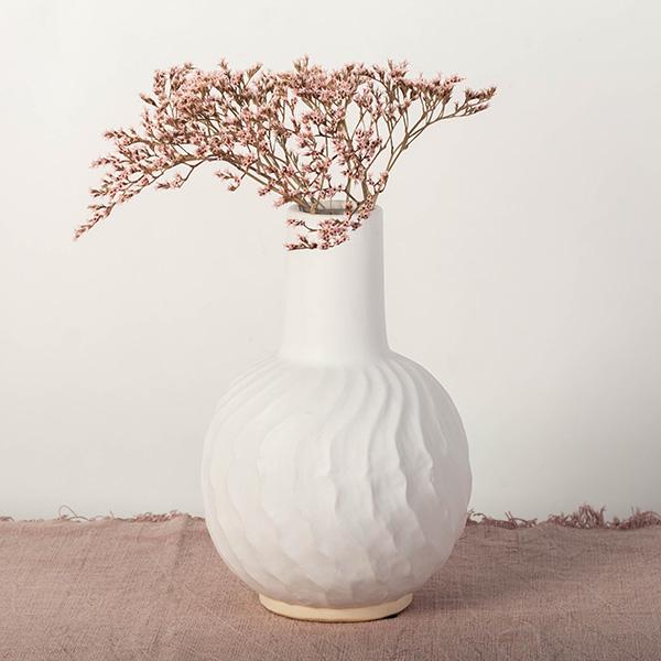 White textured vase with pink dried flowers on a light background