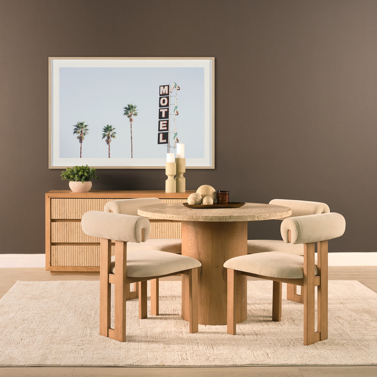 Romina round travertine dining table styled with four cream dining chairs in a warm interior