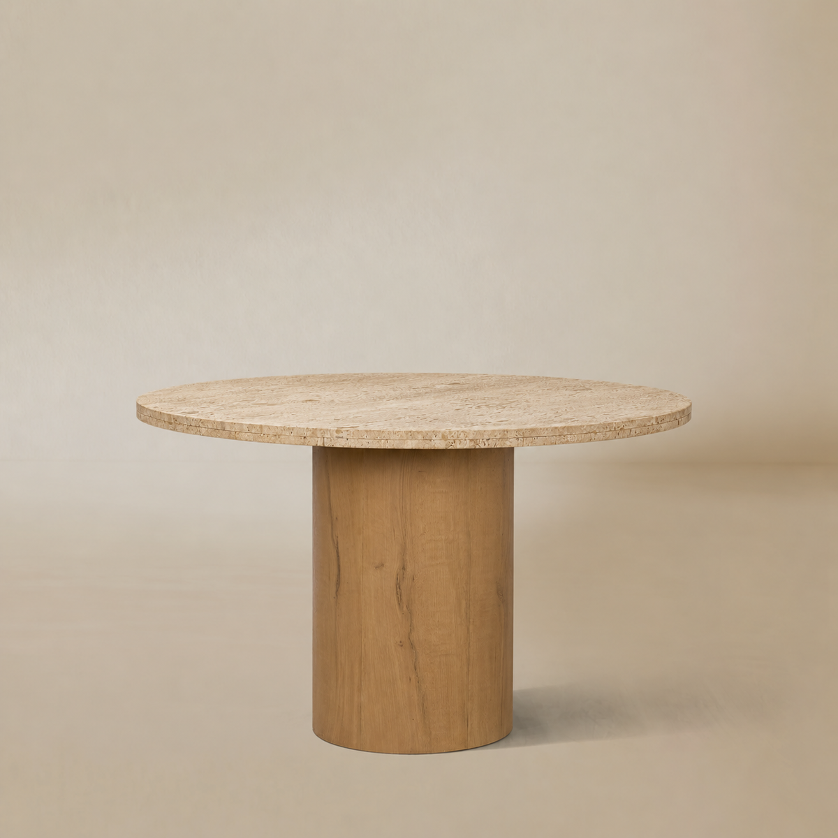 Front view of the Romina round travertine dining table with a solid oak pedestal on a clean beige background