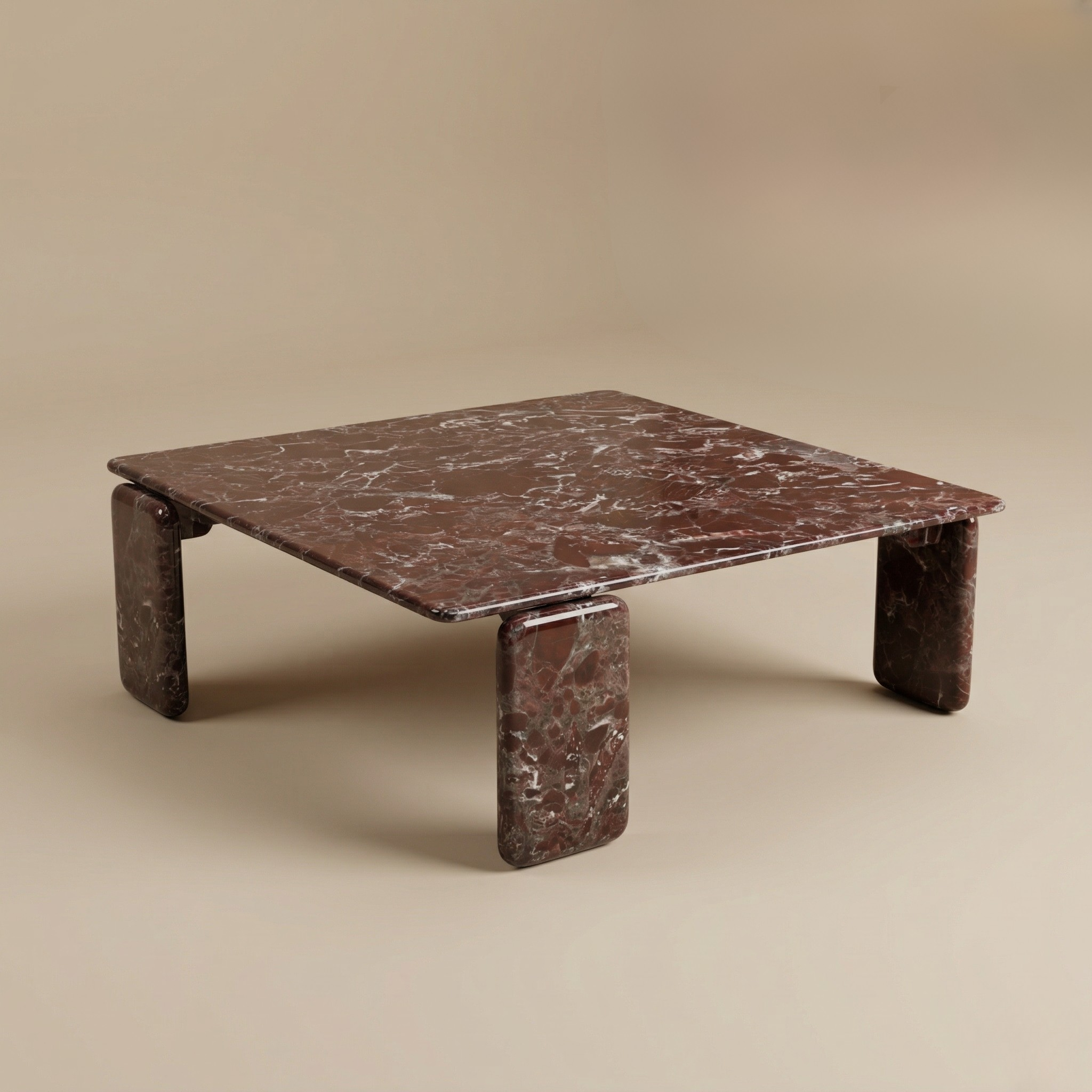 Three-quarter studio view of the Rosso Forma coffee table featuring deep red Rosso Levanto marble and pill-shaped legs.