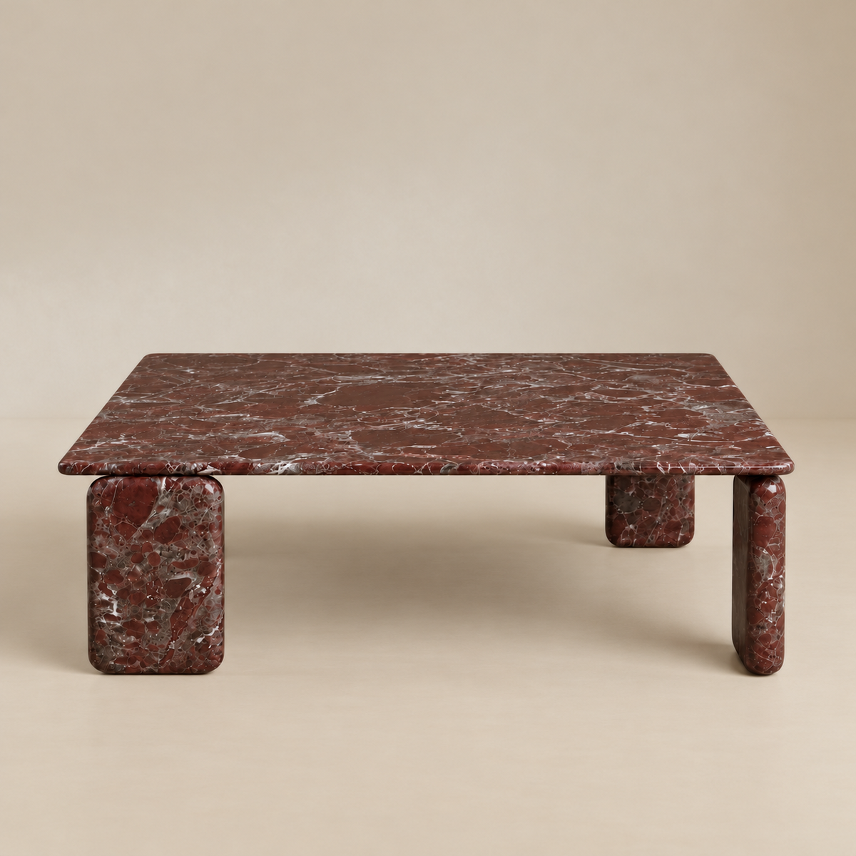 Front studio view of the Rosso Forma coffee table featuring deep red Rosso Levanto marble and pill-shaped legs.