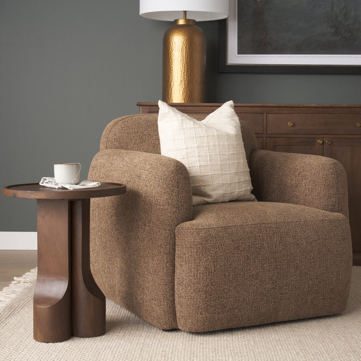 Close up lifestyle shot of the Rowan chair styled with a cream textured pillow and dark wood side table.