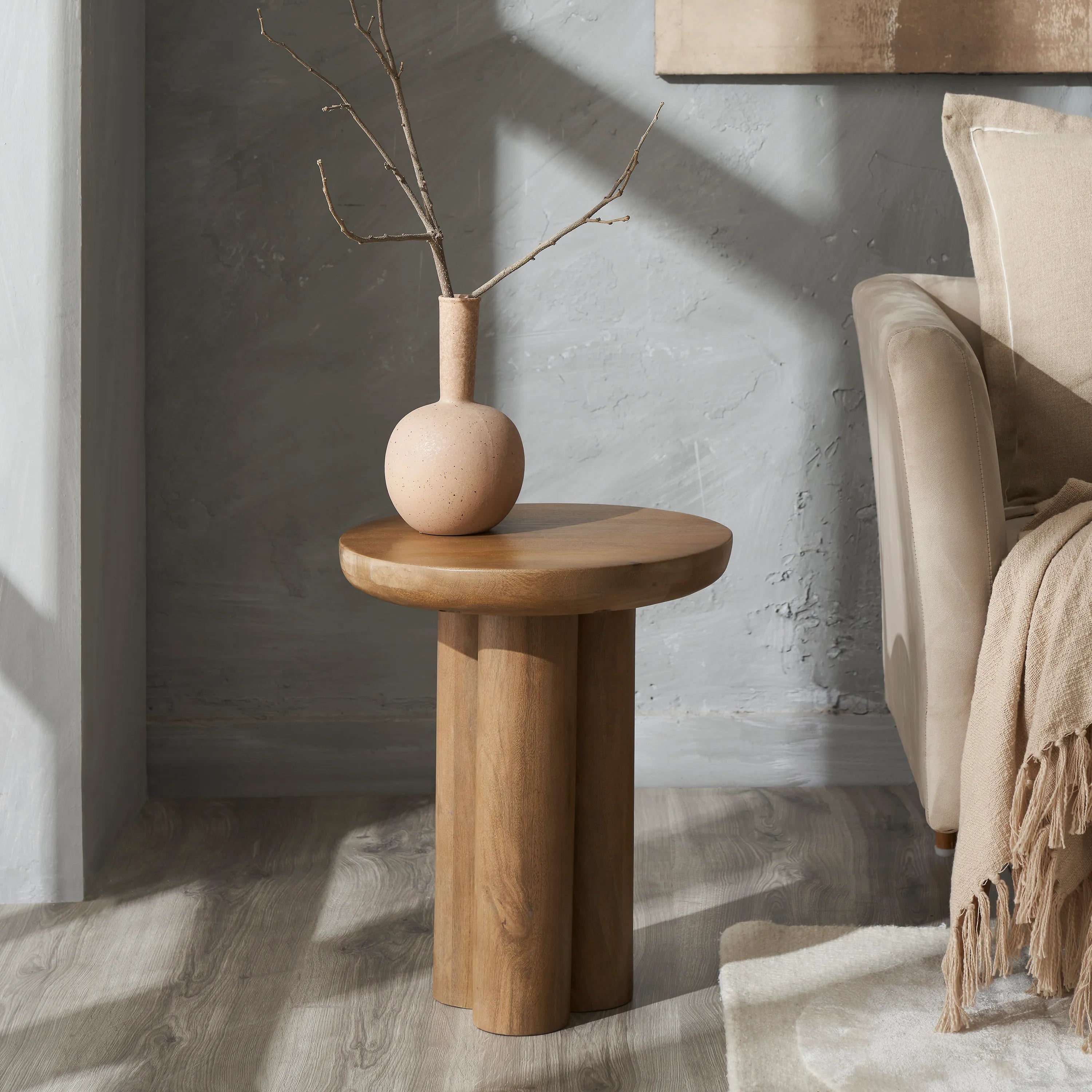 Ryn natural wood end table styled next to a beige sofa with a ceramic vase, highlighting its organic modern design and warm tones.