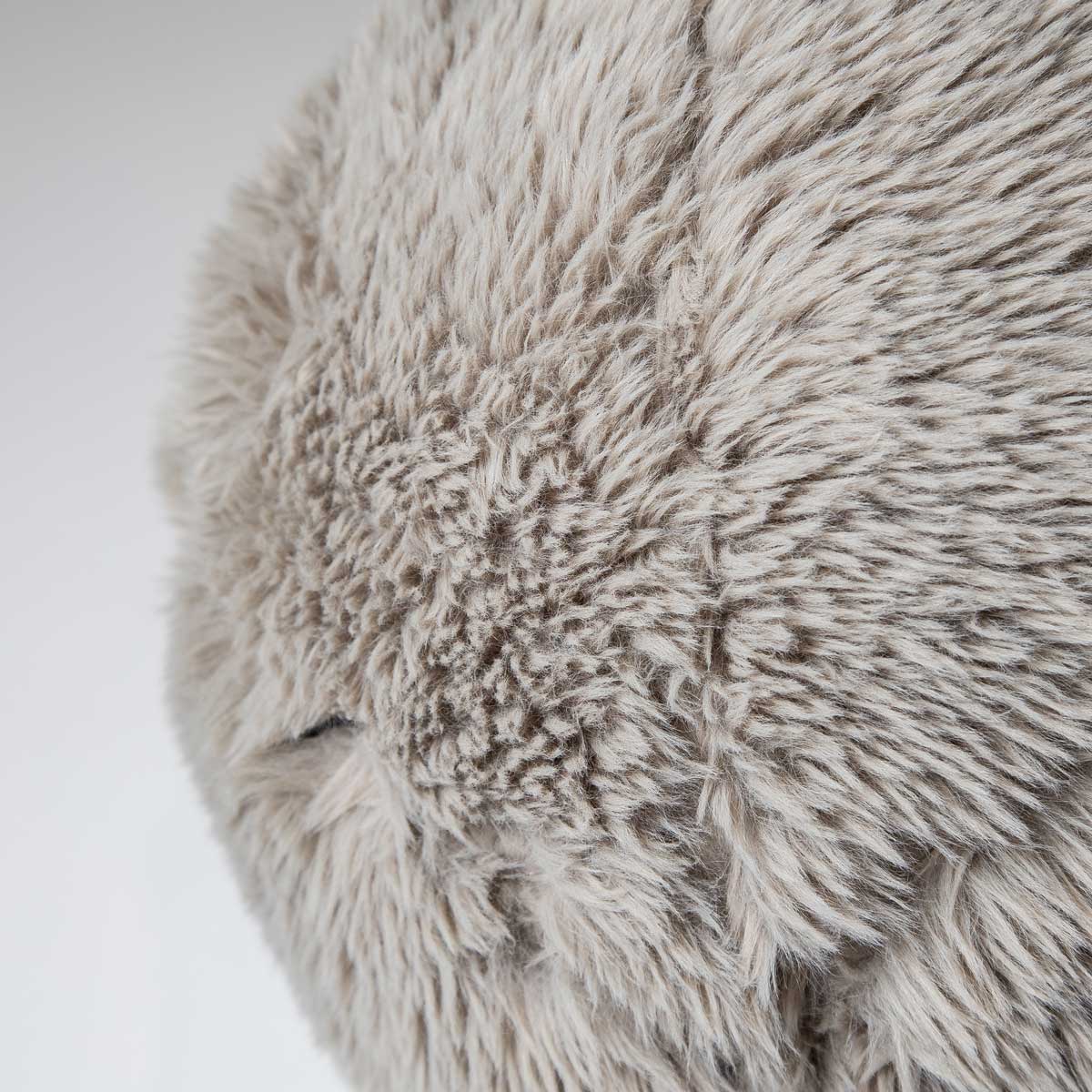 Close-up detail of the round Serenity accent pillow highlighting the soft, shaggy faux fur texture in a warm taupe.