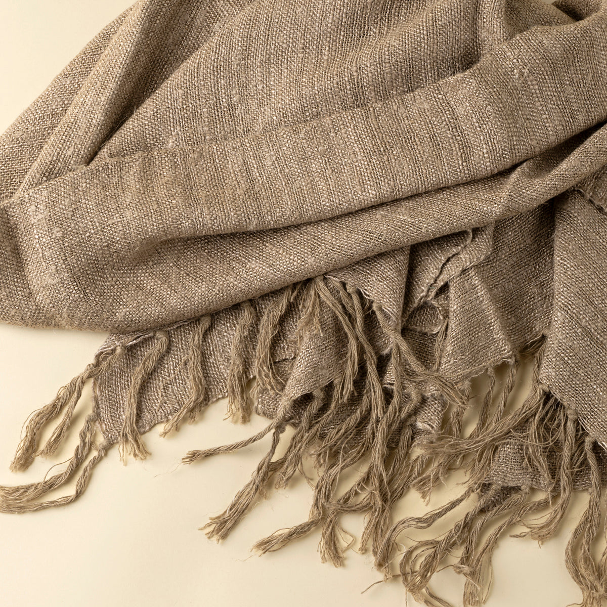 Brown woven fabric with fringes on a beige background
