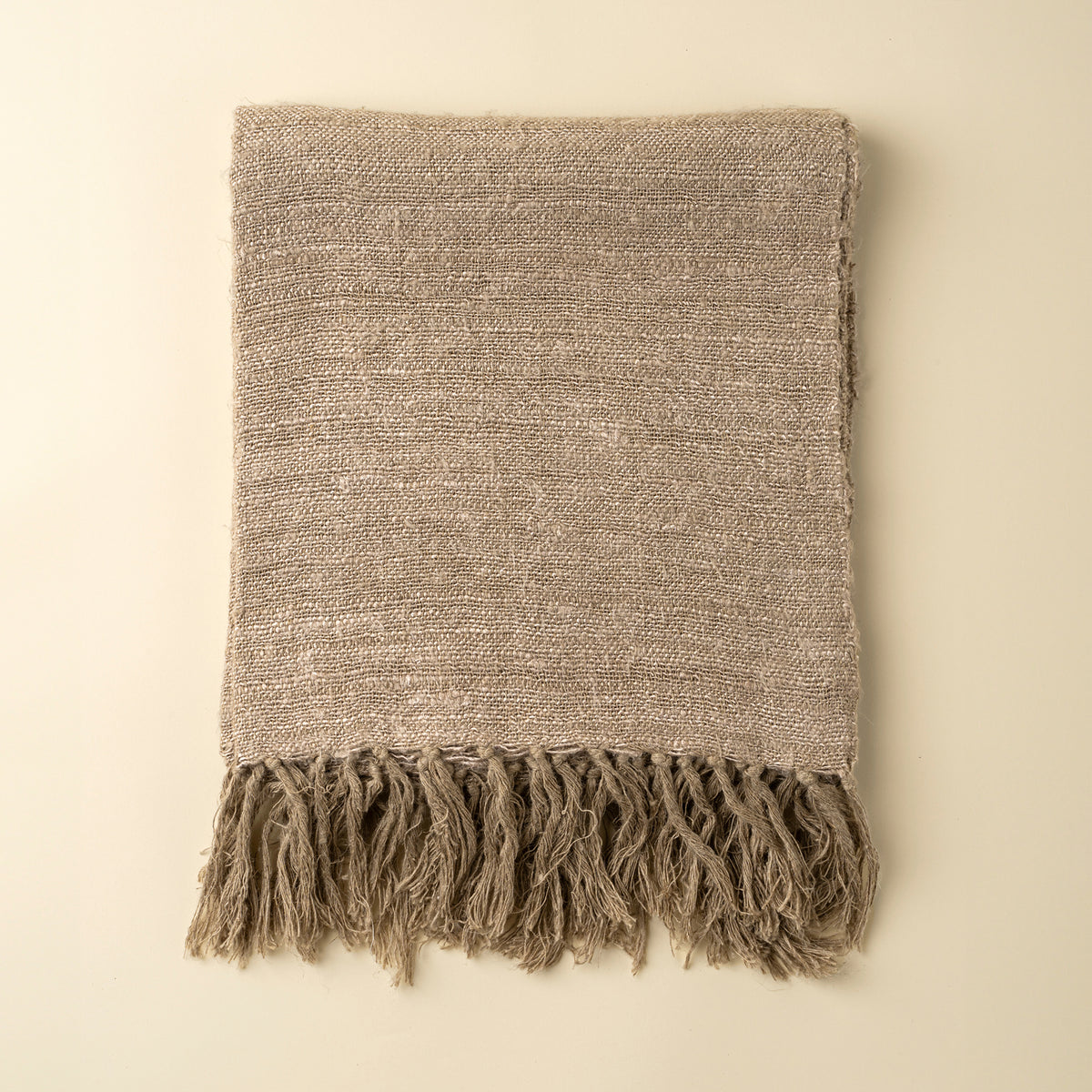 Textured blanket with fringes on a beige background