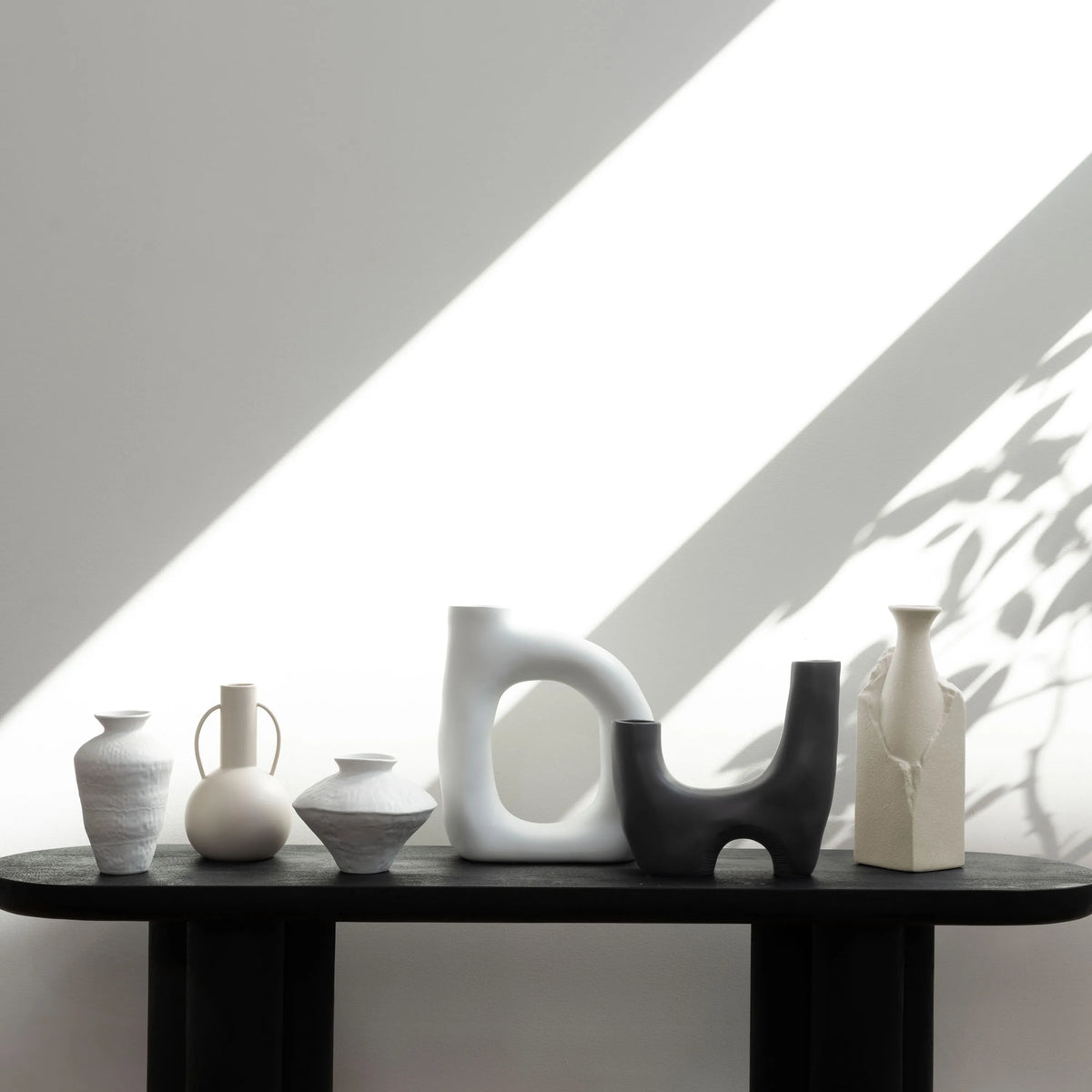Solene Ceramic Vase styled on black shelf with modern sculptural vases in soft natural light