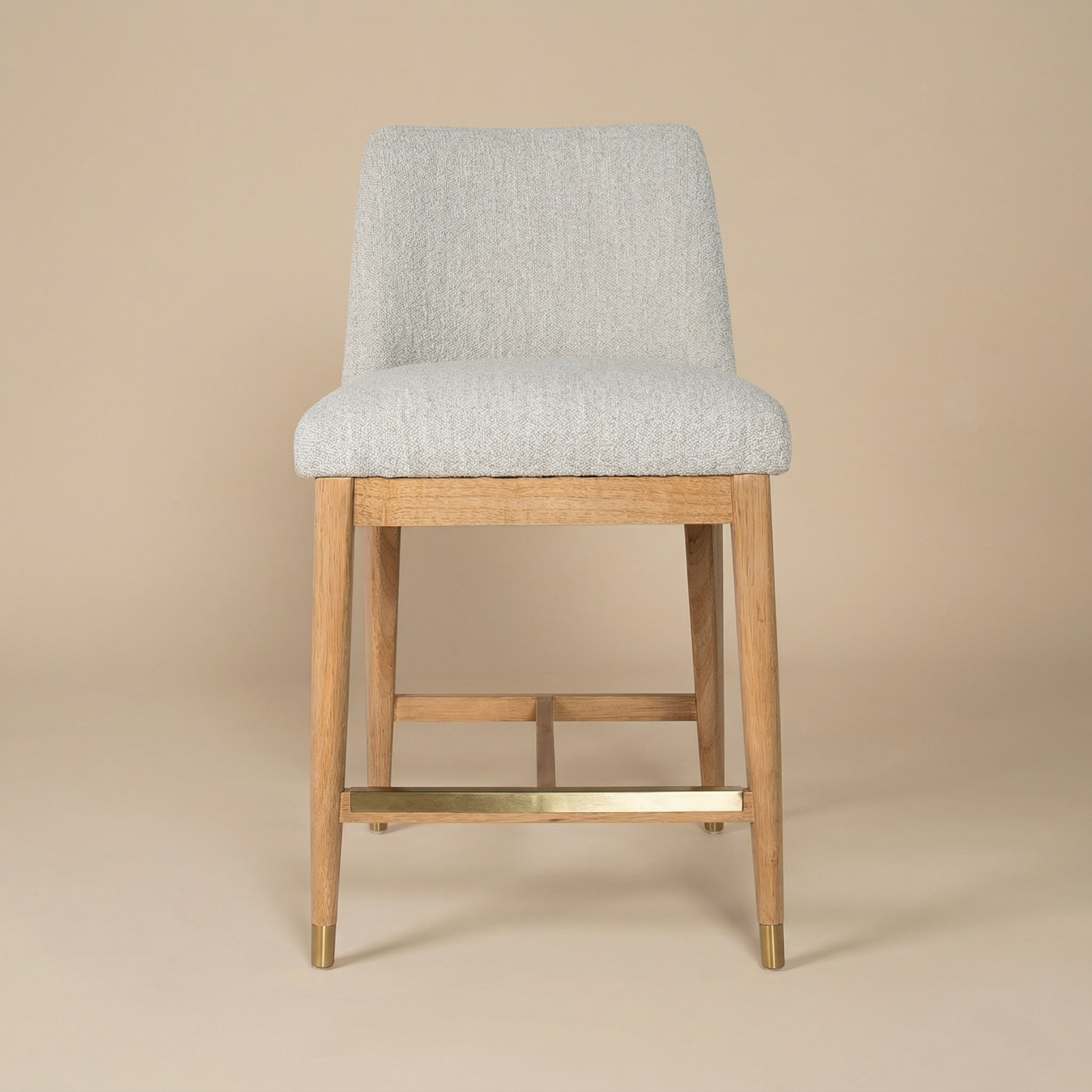 Full front view of the Sterling counter stool featuring taupe bouclé upholstery, blonde wood legs, and brushed brass ferrules.