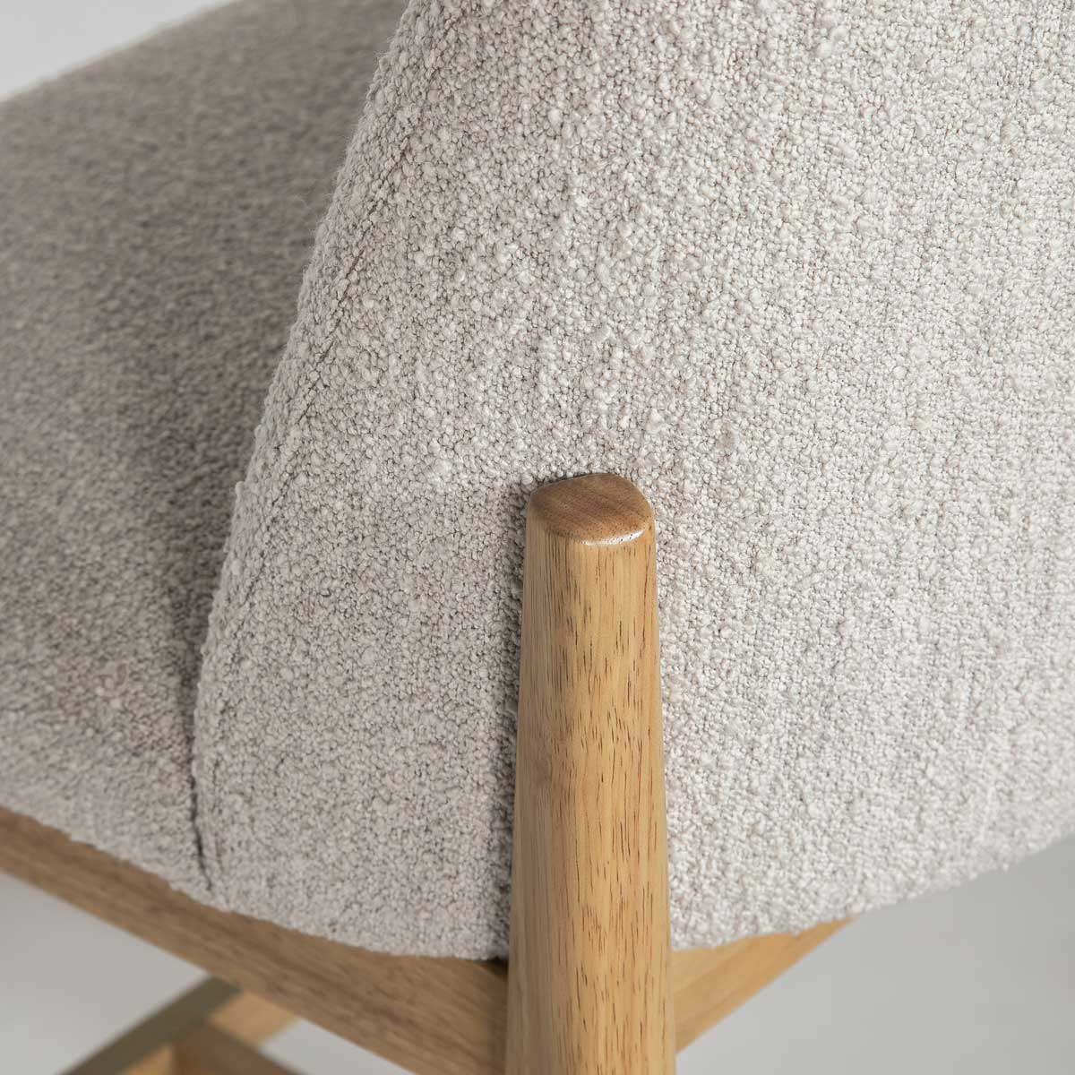Close-up detail of the Sterling stool showcasing the high-quality taupe bouclé texture and smooth wood leg joinery.