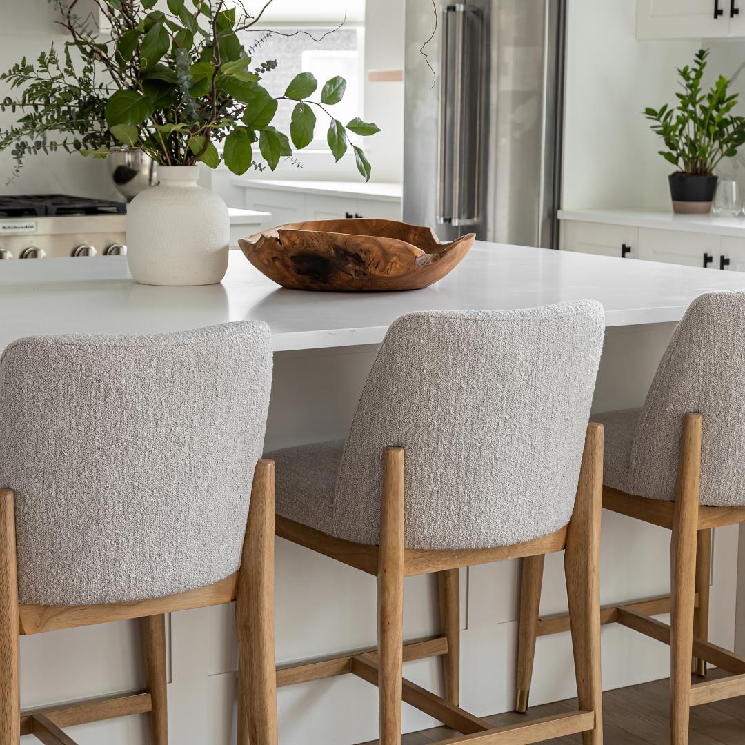 Kitchen with a white island, gray bar stools, and a refrigerator.