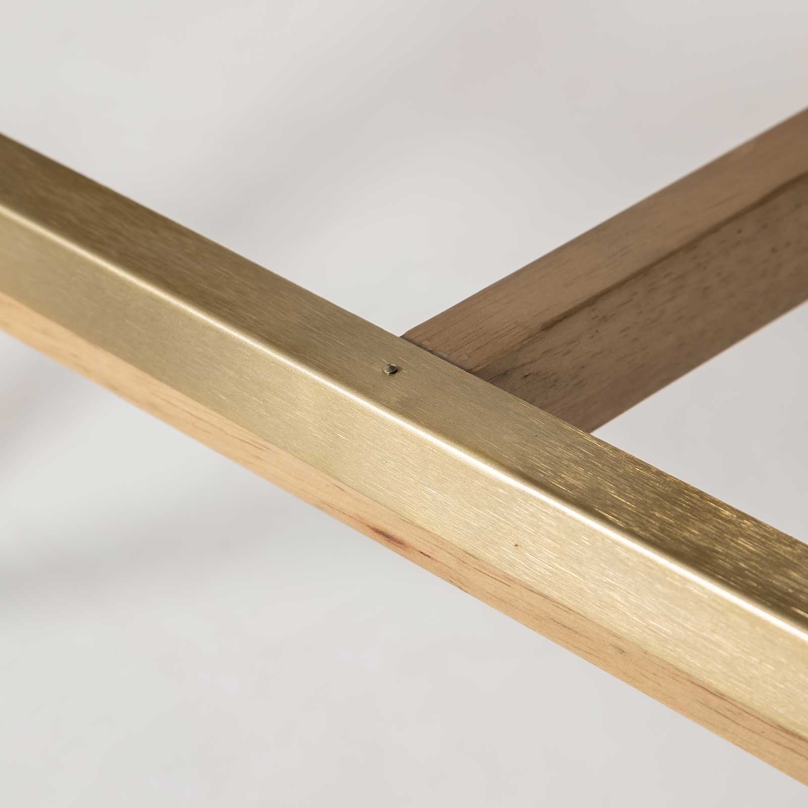 Close-up of the Sterling counter stool's footrest featuring a protective brushed brass metal plate.