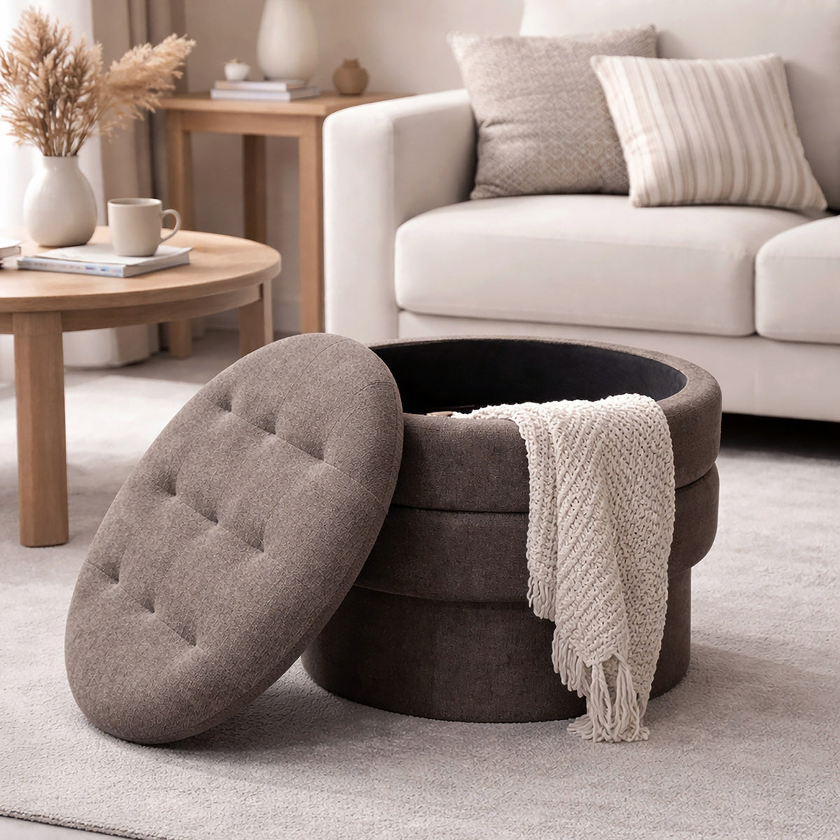 Round storage ottoman with a tufted lid in a living room setting.