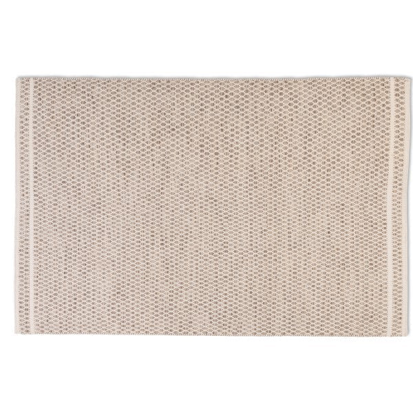Full top-down view of the Theo hand-woven wool rug in a warm husk oatmeal color, showcasing its geometric woven pattern and banded ends