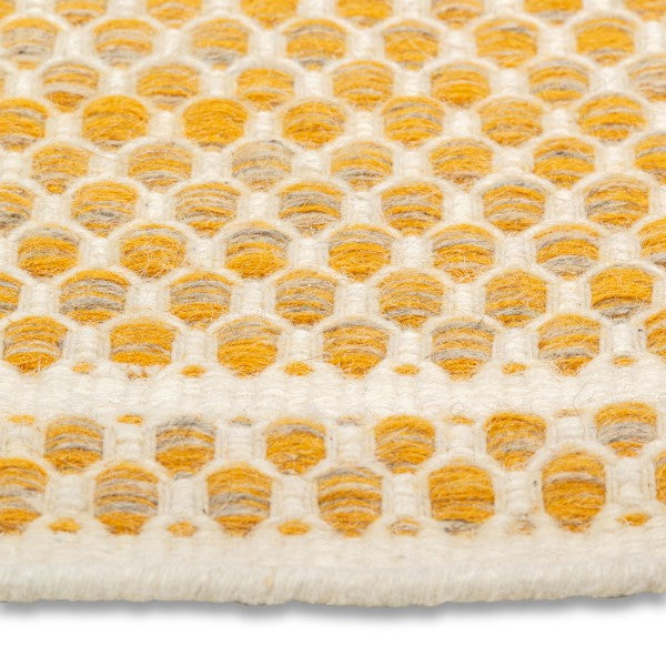 Detailed close-up of the chunky geometric honeycomb weave on the yellow and cream Theo hand-woven wool rug