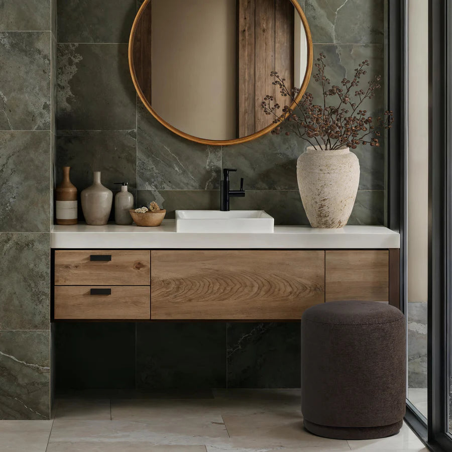 Bathroom with wooden vanity, round mirror, and decorative elements.
