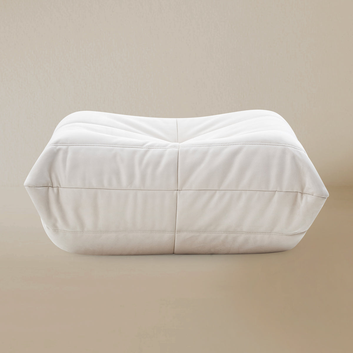 Front view of the White TOGO ottoman on a beige background