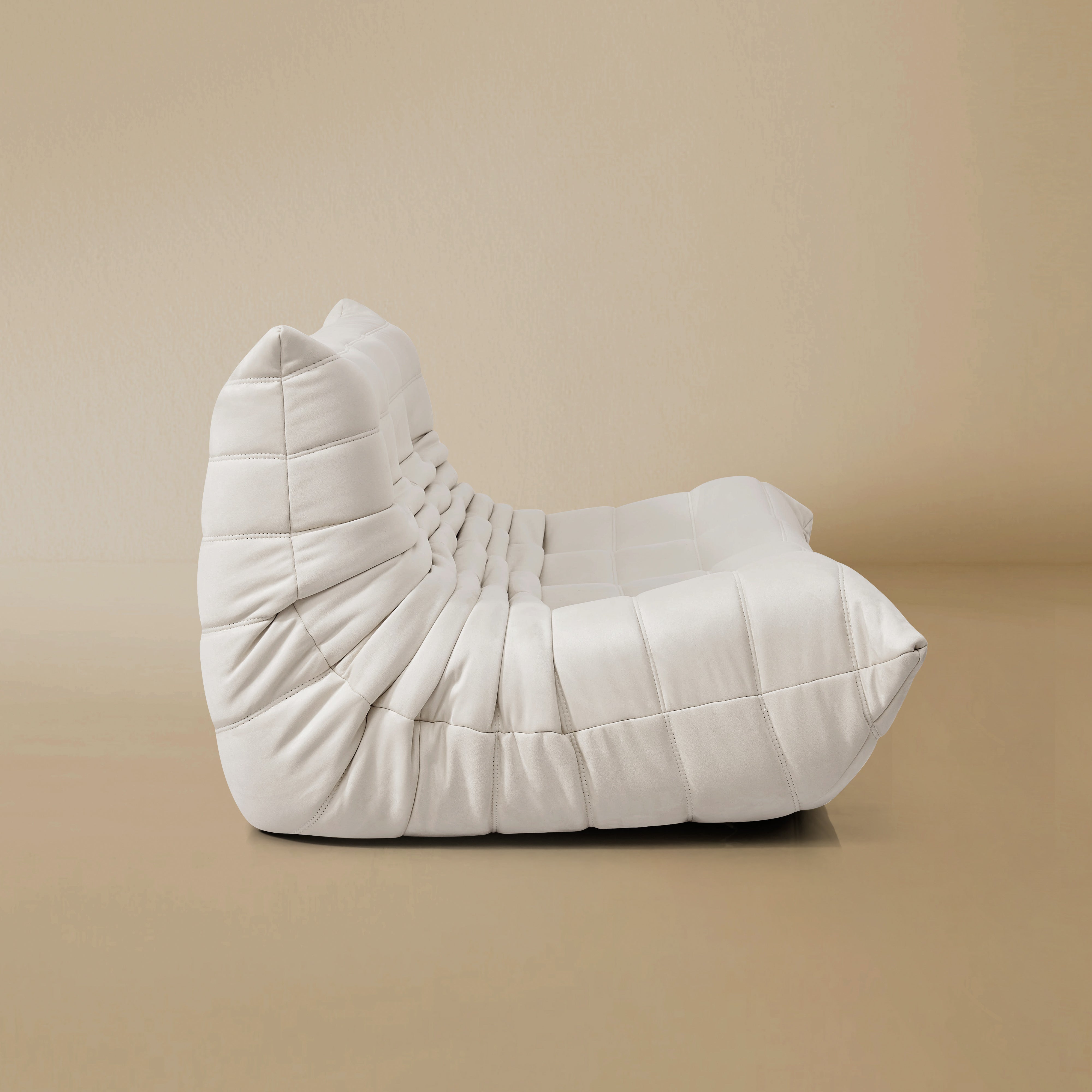 Side view of the TOGO Three Seater Lounger in a light beige studio background