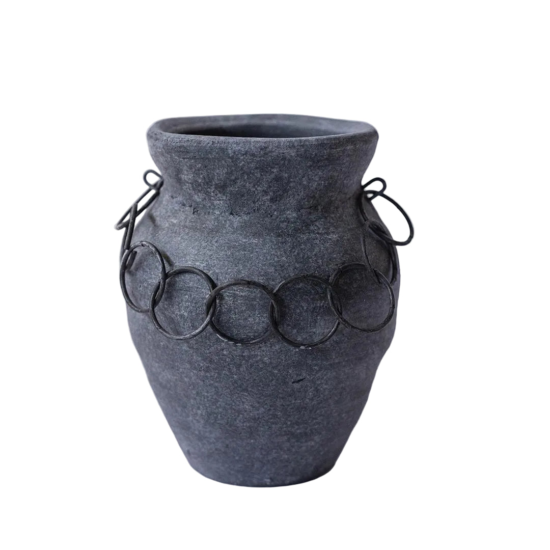Gray textured vase with circular metal accents on a white background