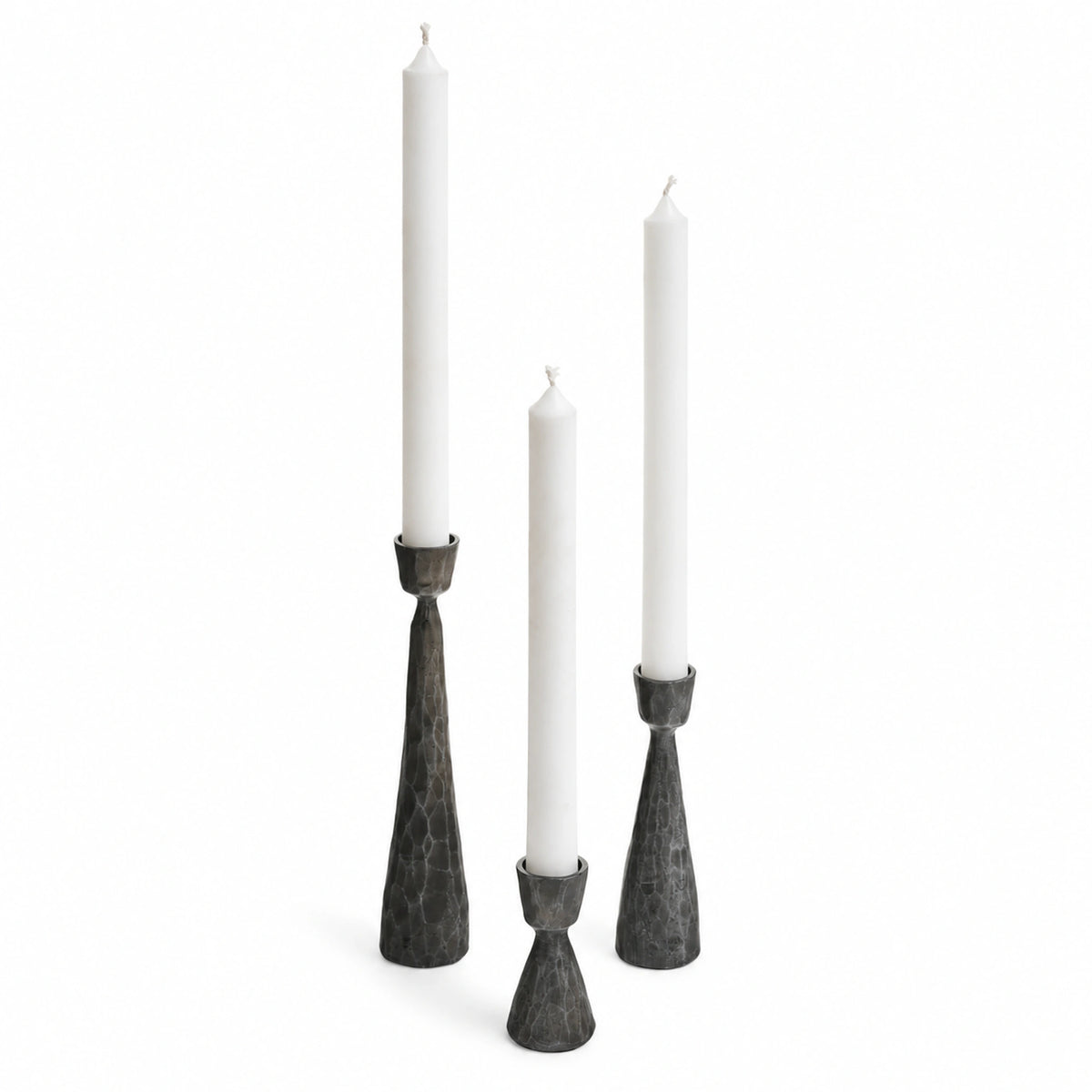 Varen set of three antique black hand-hammered iron taper candle holders on a white background.