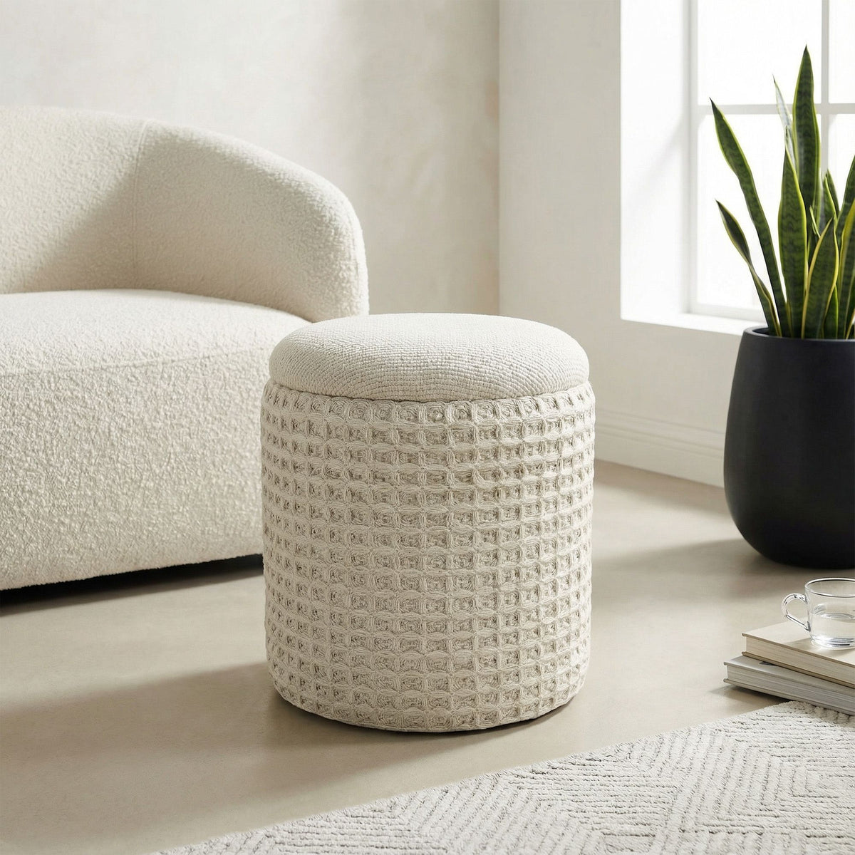 Textured ottoman in a living room setting with a chair and plant.