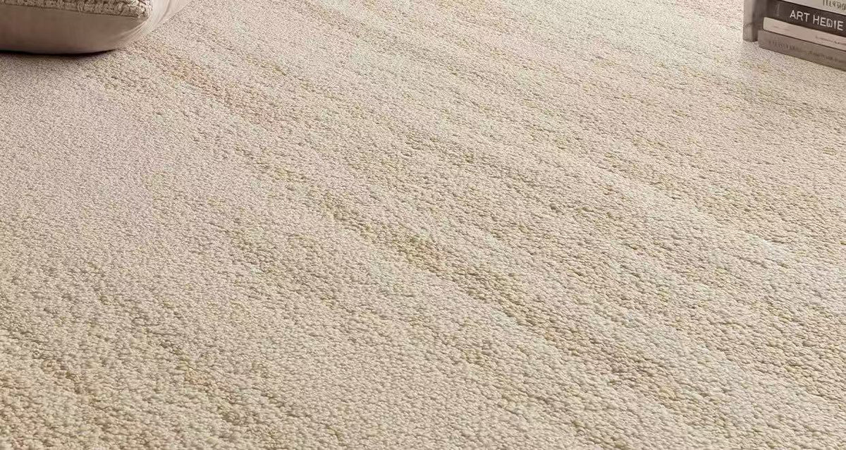 Close-up of the rug in a room setting, showing the warm ivory pile and subtle tonal texture.
