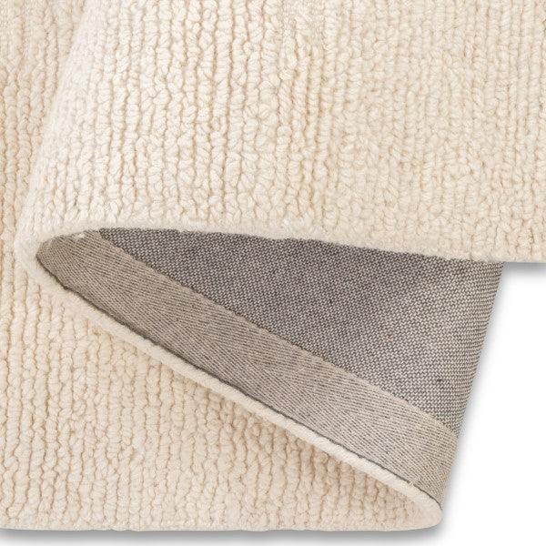 Folded edge view of the vinne diamond rug, demonstrating the thick wool pile and the sturdy finished backing underneath.