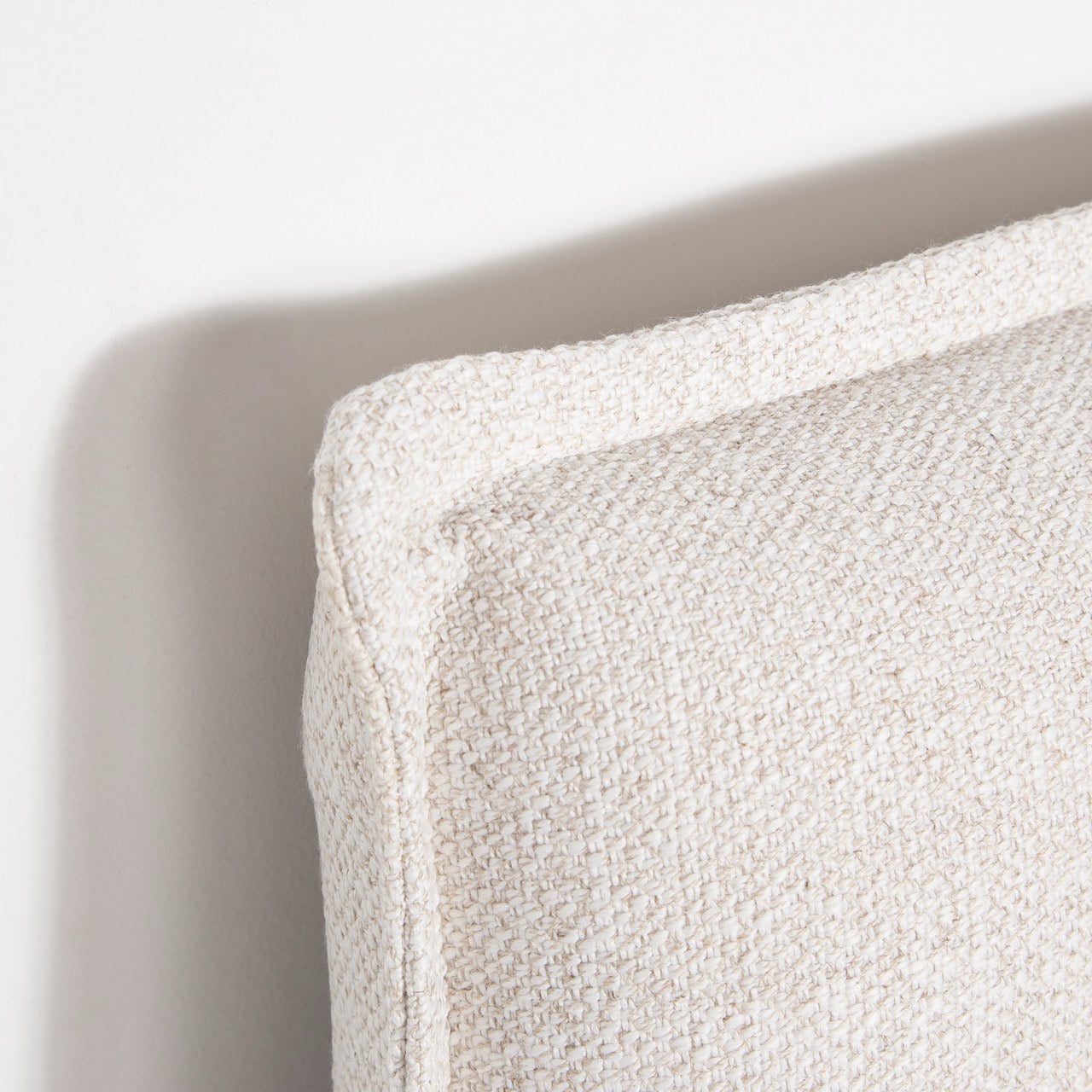 Macro close-up view highlighting the textured cream linen-blend fabric and the precise stitching of the French seam.