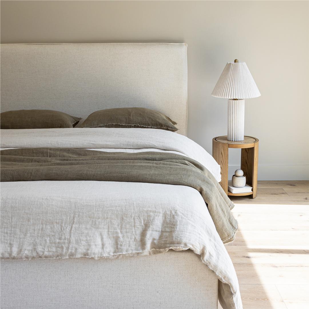 Front view of the Vivienne bed styled with a pleated table lamp and textured linen pillows in a bright, airy room.