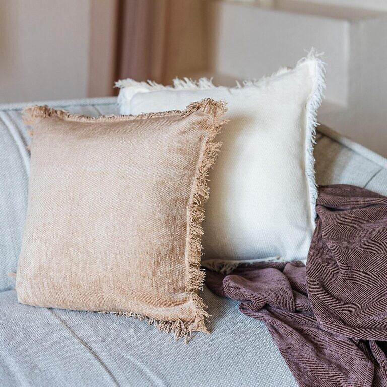 Textured pillows on a sofa with a blanket