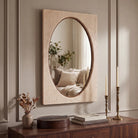 Adeline Faux Travertine Wall Mirror styled above a dark wood console in a warm neutral interior.