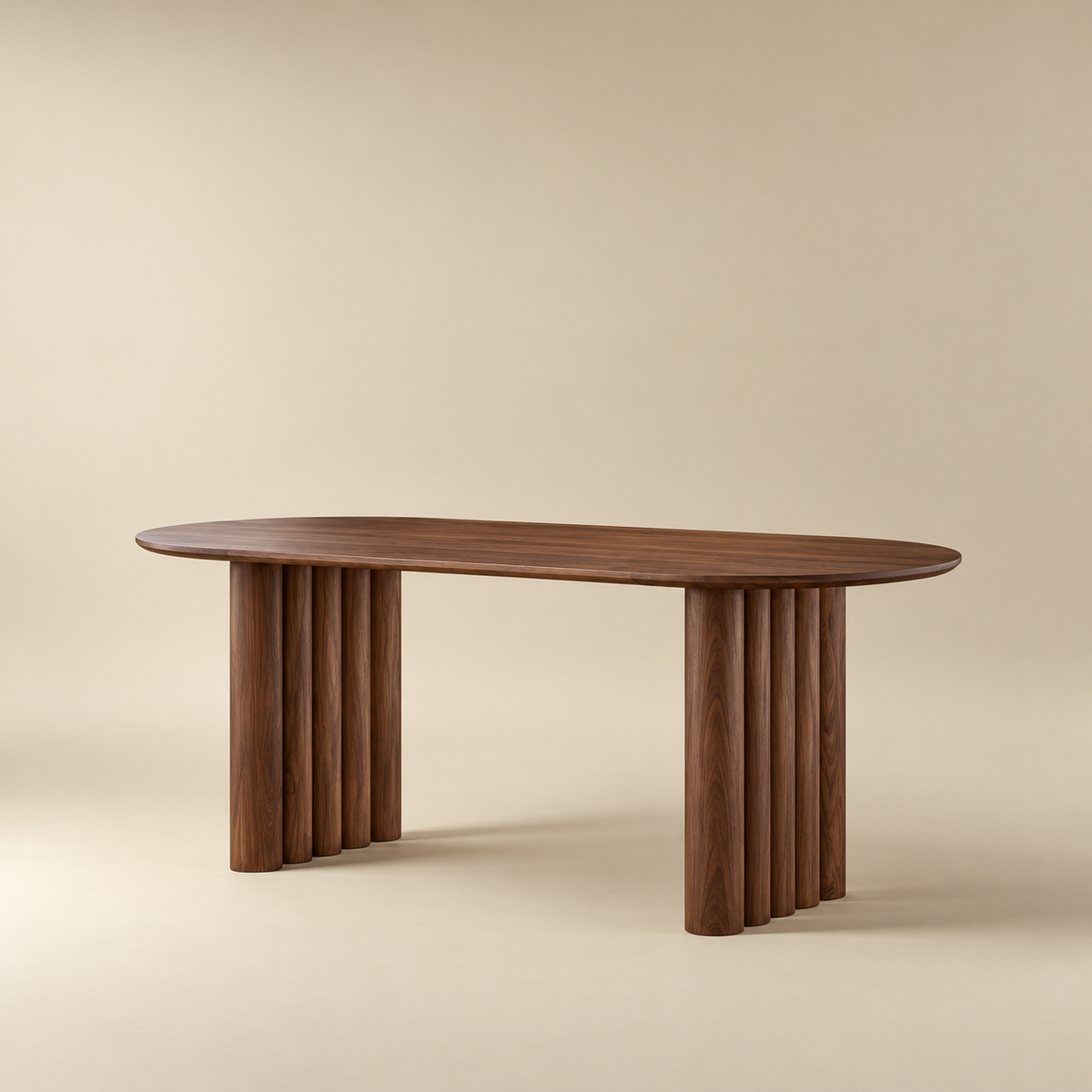 Adrian dining table with a rich walnut finish, supported by two central columns of fluted round legs, set against a warm beige studio background.