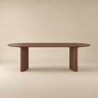 Adrian dining table with fluted pedestal legs, shown against a solid beige background.