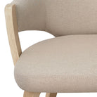 Close-up of a beige upholstered chair with wooden legs on a white background featuring the Alden Dining Chair