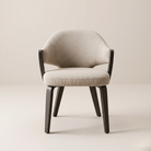 Beige upholstered chair with dark wooden legs on a light beige background featuring the Alden Dining Chair