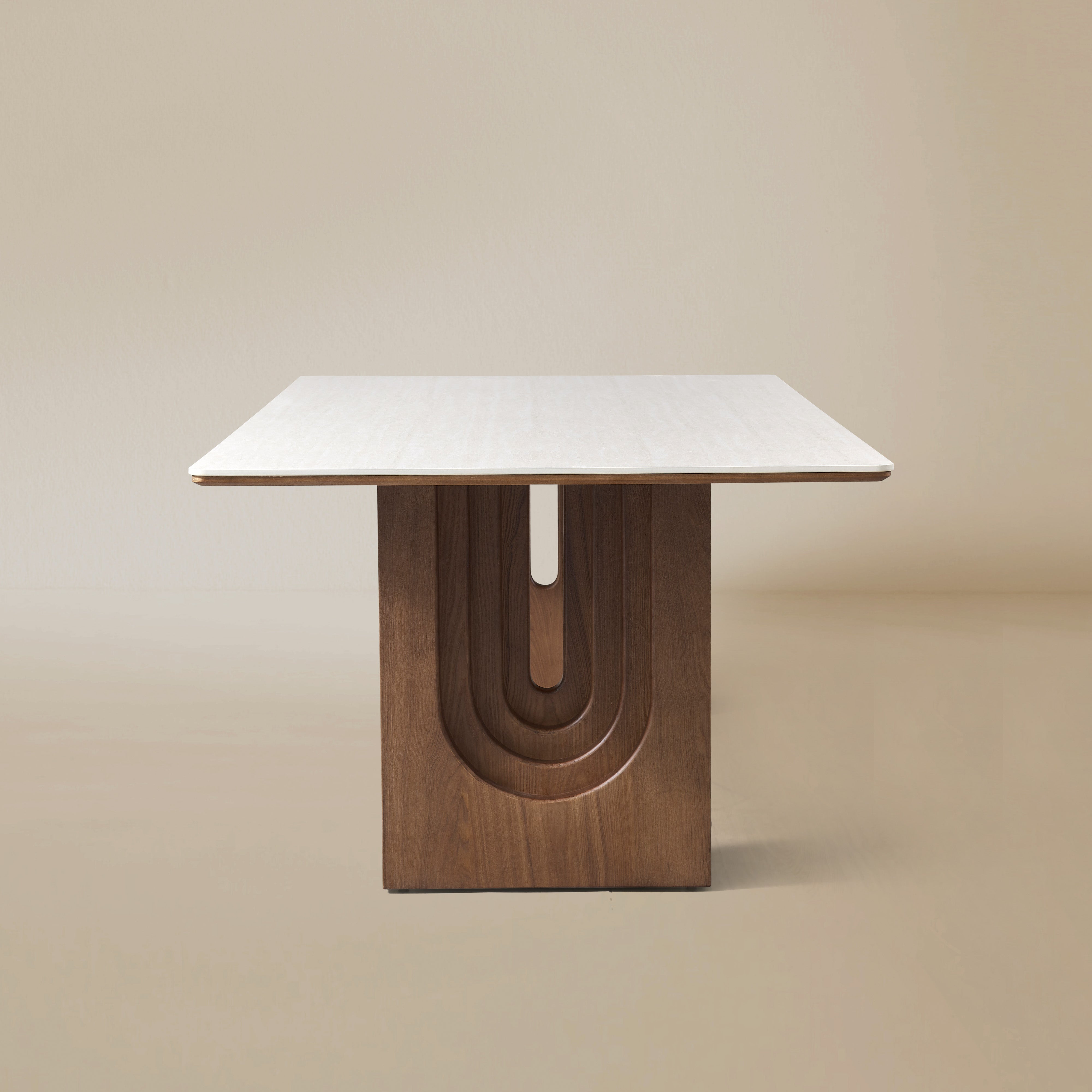 Side view of the Arcadian Dining Table with a white travertine top and walnut wooden legs on a beige background