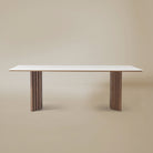 Arcadian Dining Table with a white travertine top and walnut wooden legs on a beige background