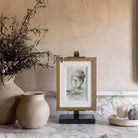 Arvessa marble and brass display easel holding framed artwork on a console