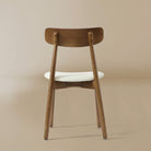 Back profile of the Ash Classic dining chair featuring a solid wood frame with a dark walnut finish, curved backrest, and cream upholstered seat