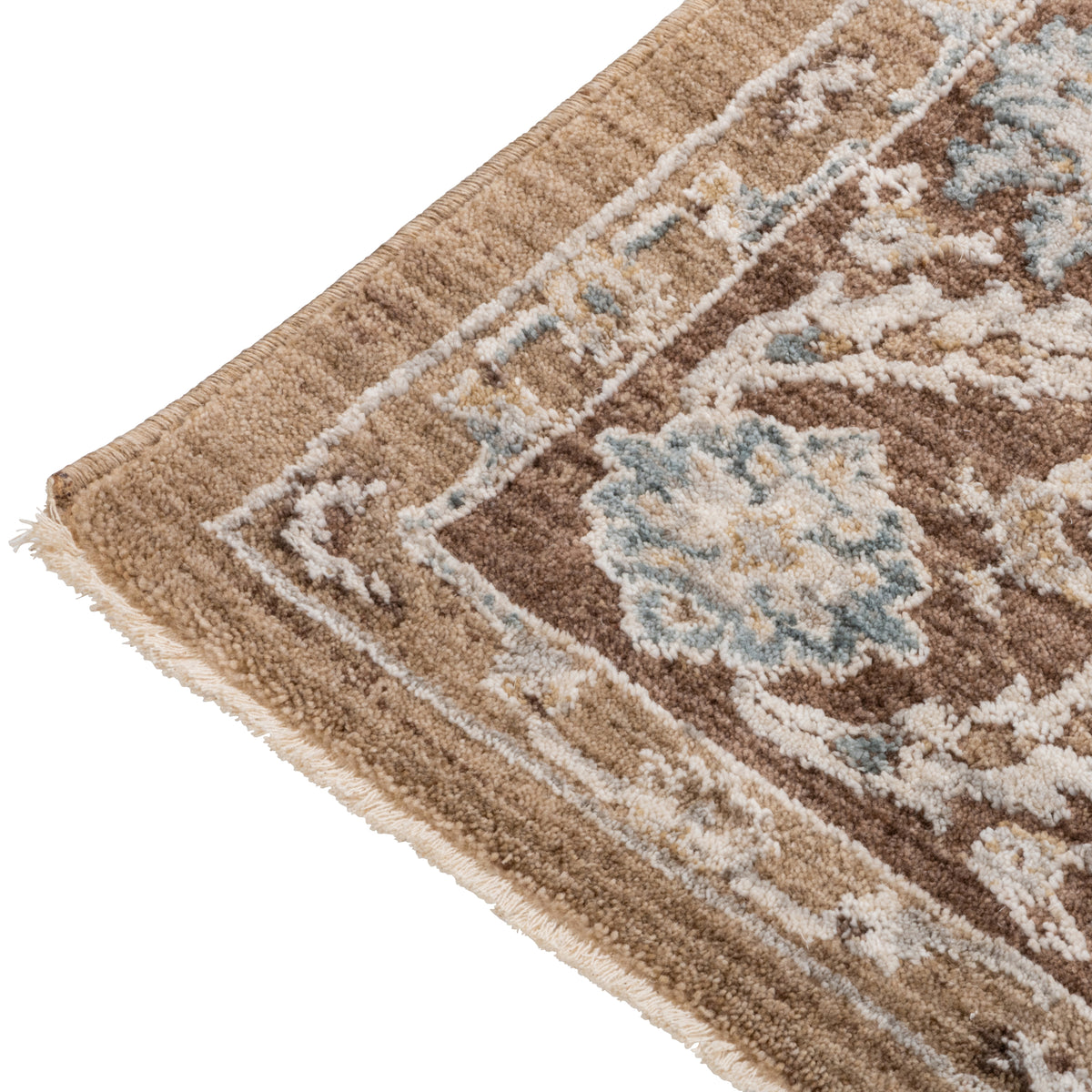 Corner detail of the Aurelia Vintage Floral Rug in Mocha showing the warm brown border, floral pattern and short fringed edge.