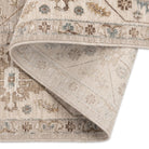 Aurelia Vintage Floral Rug in Sand folded back to show the patterned surface, stitched edge, and woven backing.